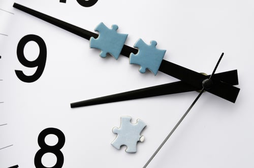 Delivery time Minute hand of analog electric clock carries two pieces of jigsaw puzzle, with a third on the white face